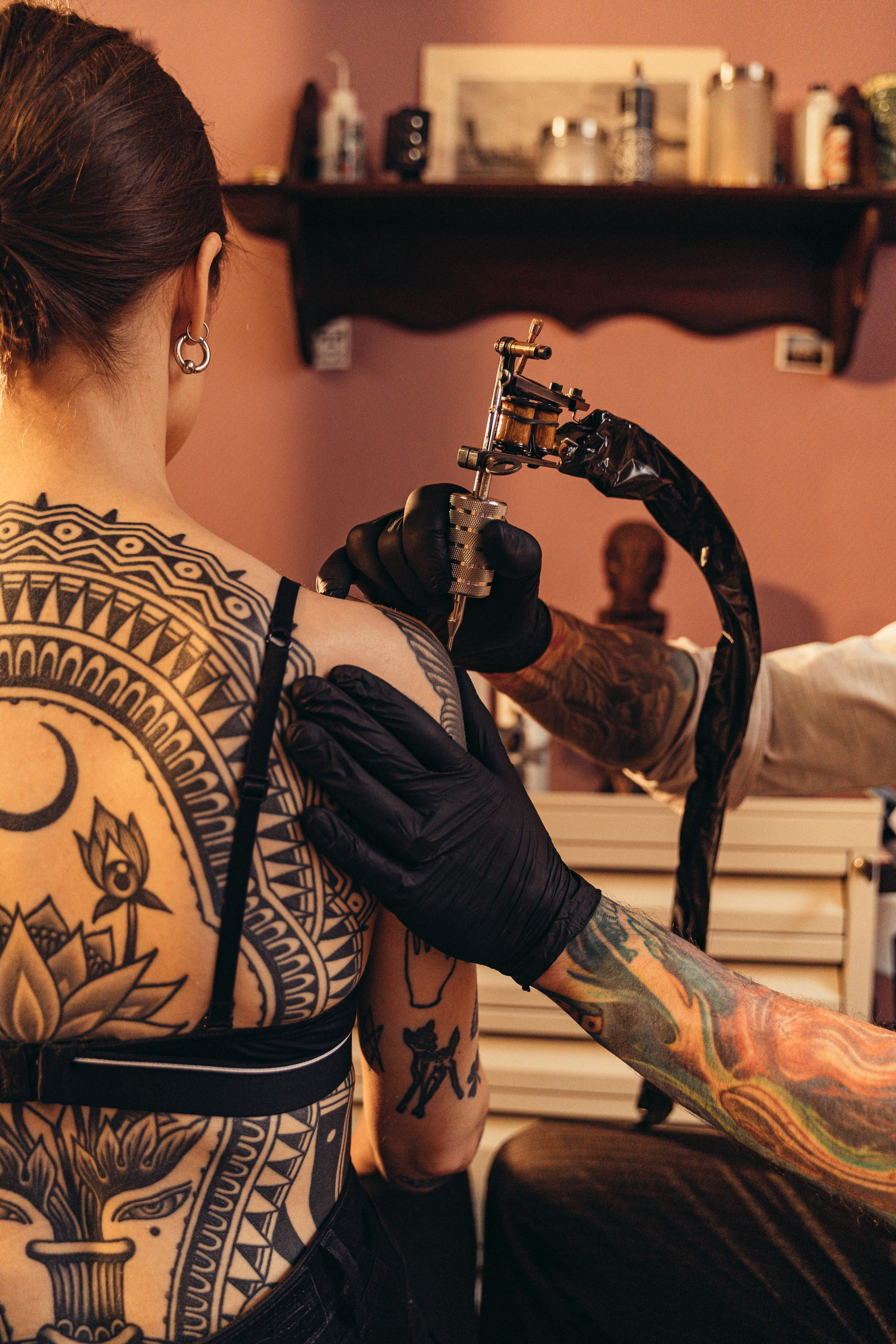 Tatuadora com grande mandala nas costas trabalhando em estúdio
